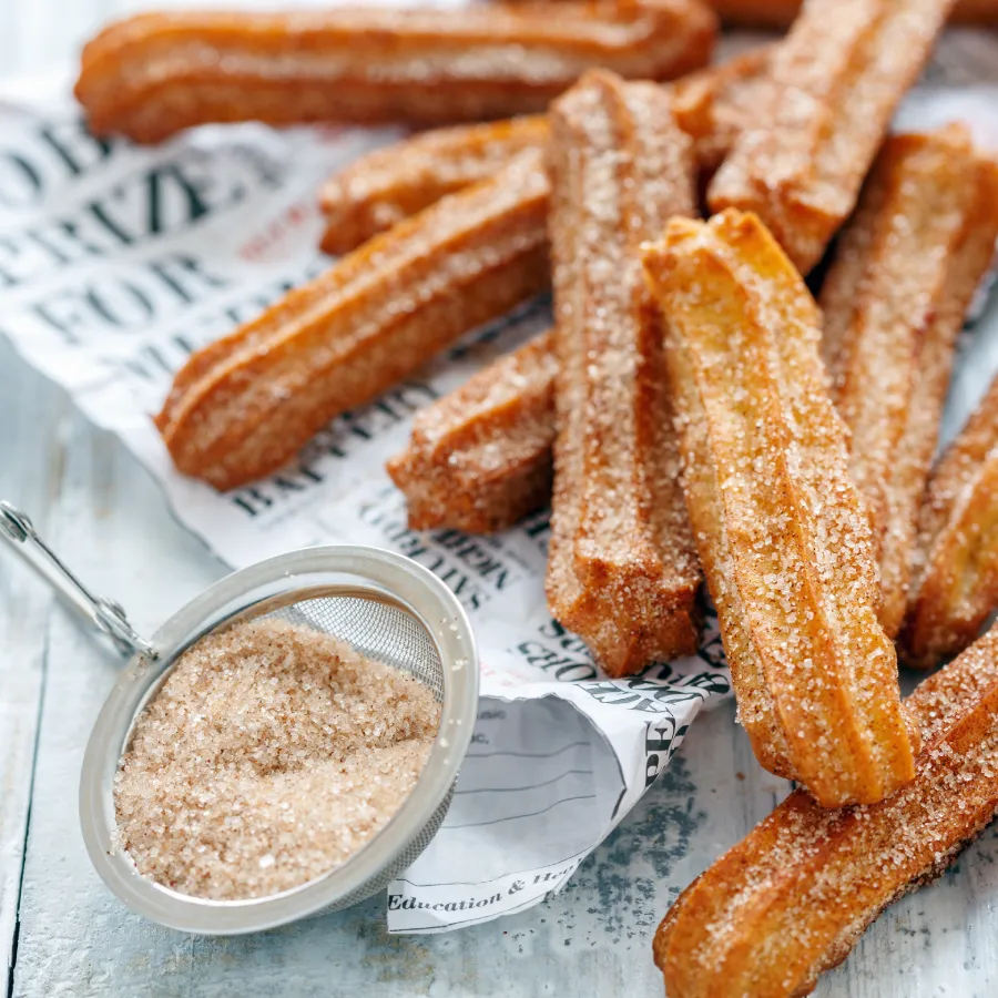 Churros croustillants avec sucre Churros saupoudrés de sucre sur papier journal
