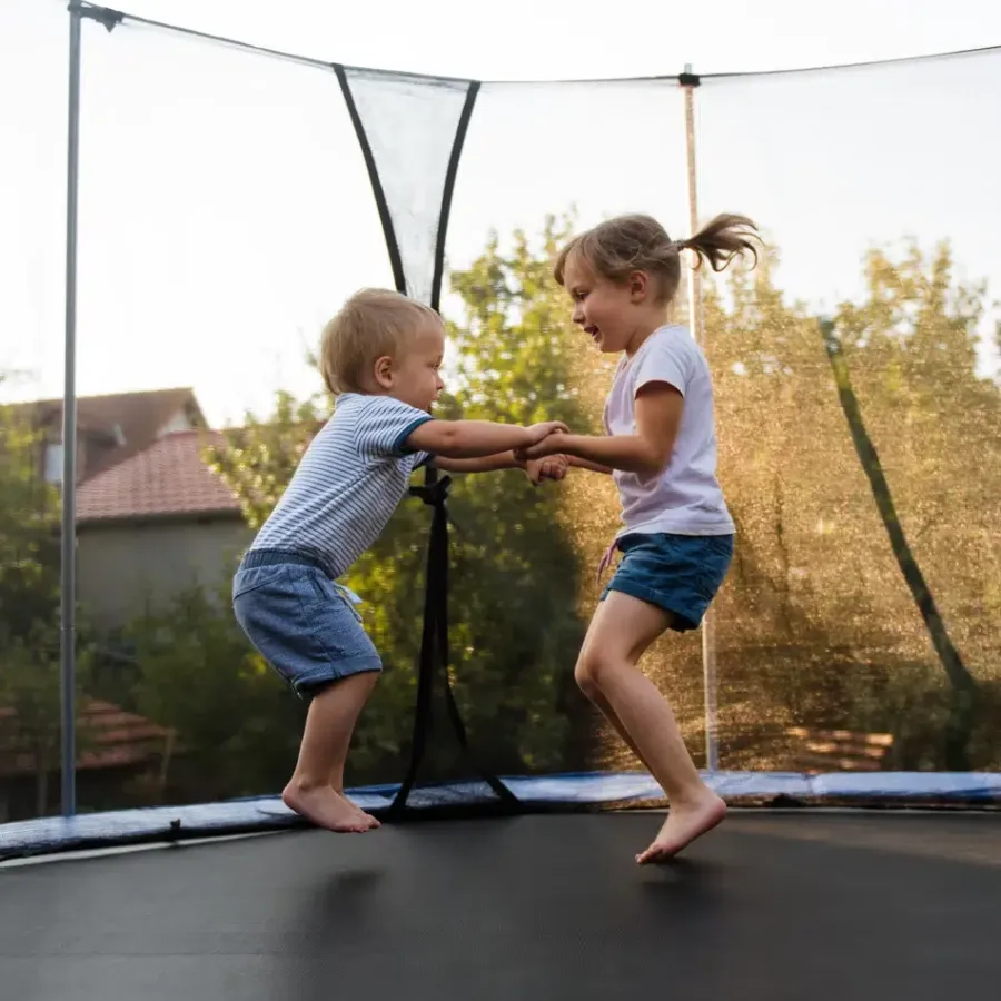 Enfants s\'amusant sur un trampoline Deux enfants jouent sur un trampoline en extérieur.
