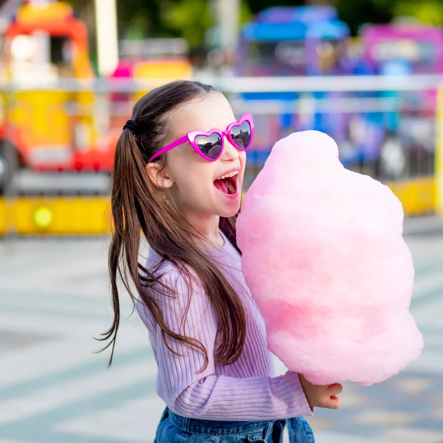 Enfant avec barbe à papa et lunettes roses Fille avec lunettes roses tenant une barbe à papa.